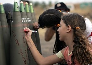 Żydowskie dziewczynki piszą życzenia na bombach, które wkrótce spadną Palestyńczykom na głowę, fot: AFP